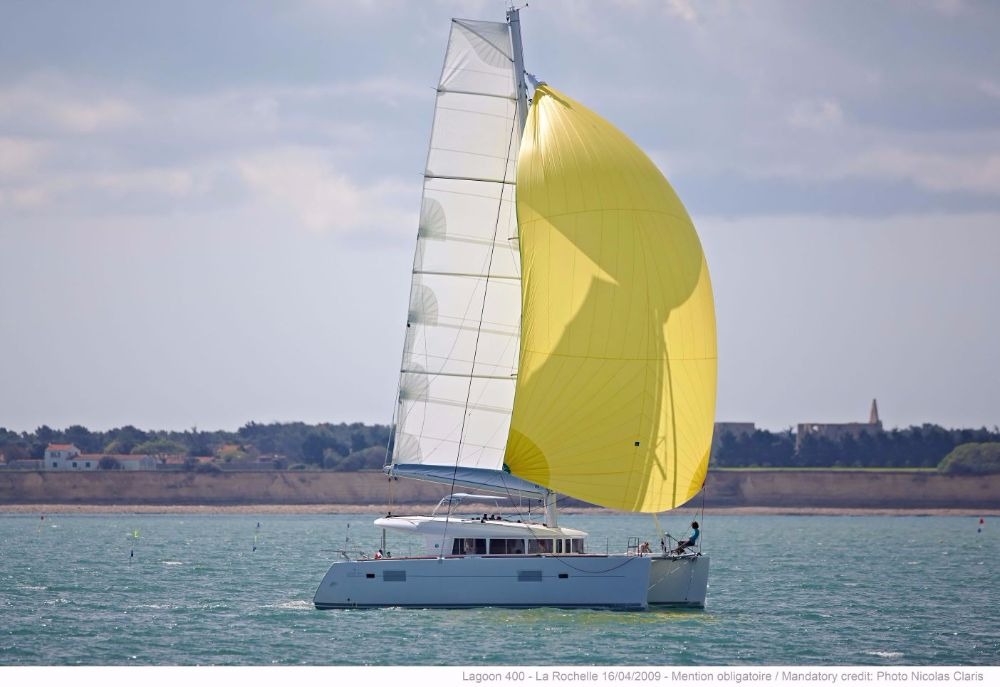 Lagoon 400 catamaran under full mainsail and yellow gennaker, seen from astern on open water