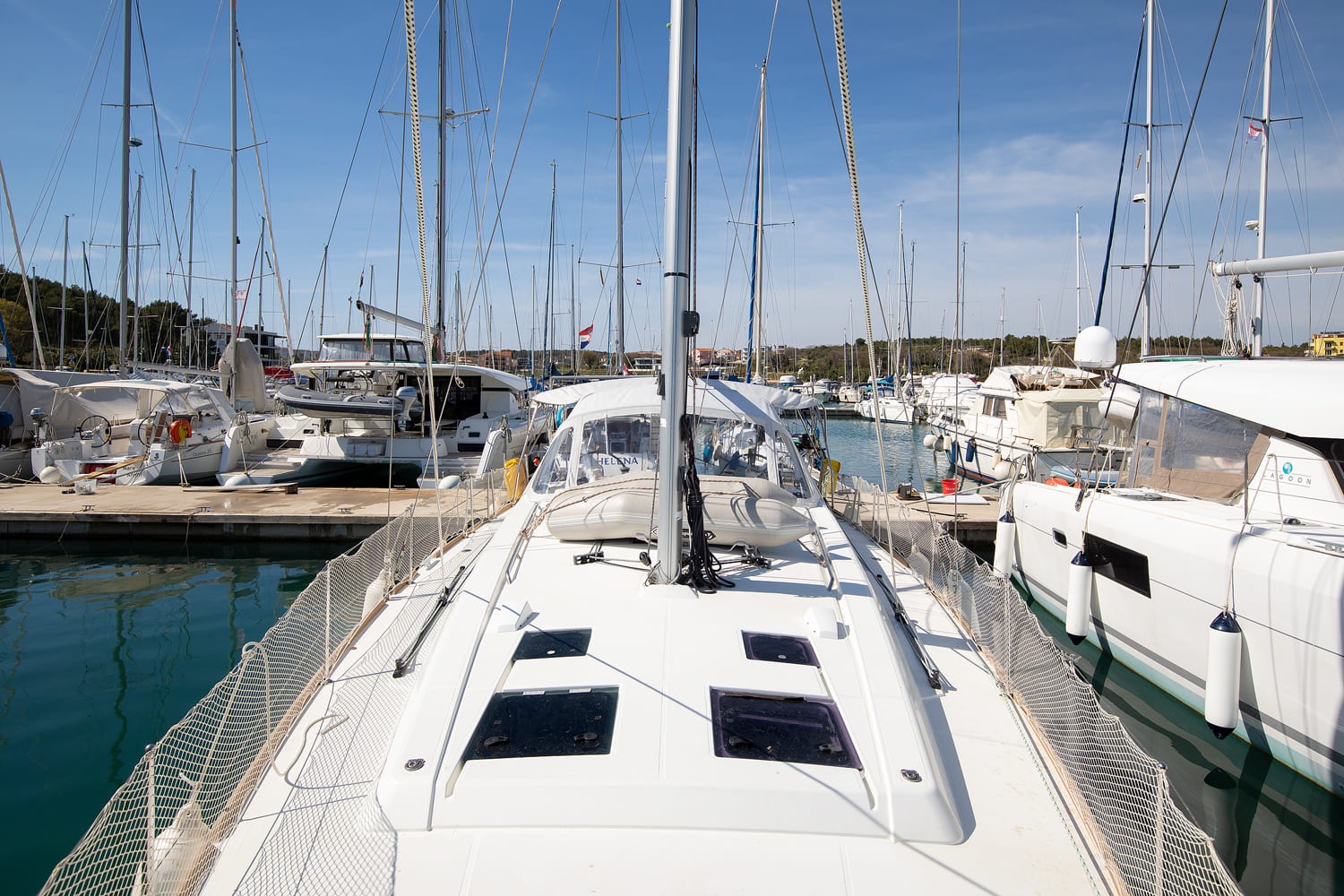 Foredeck of the Oceanis 45 looking aft, with deck hatches, guard netting and the tender stowed ahead of the sprayhood