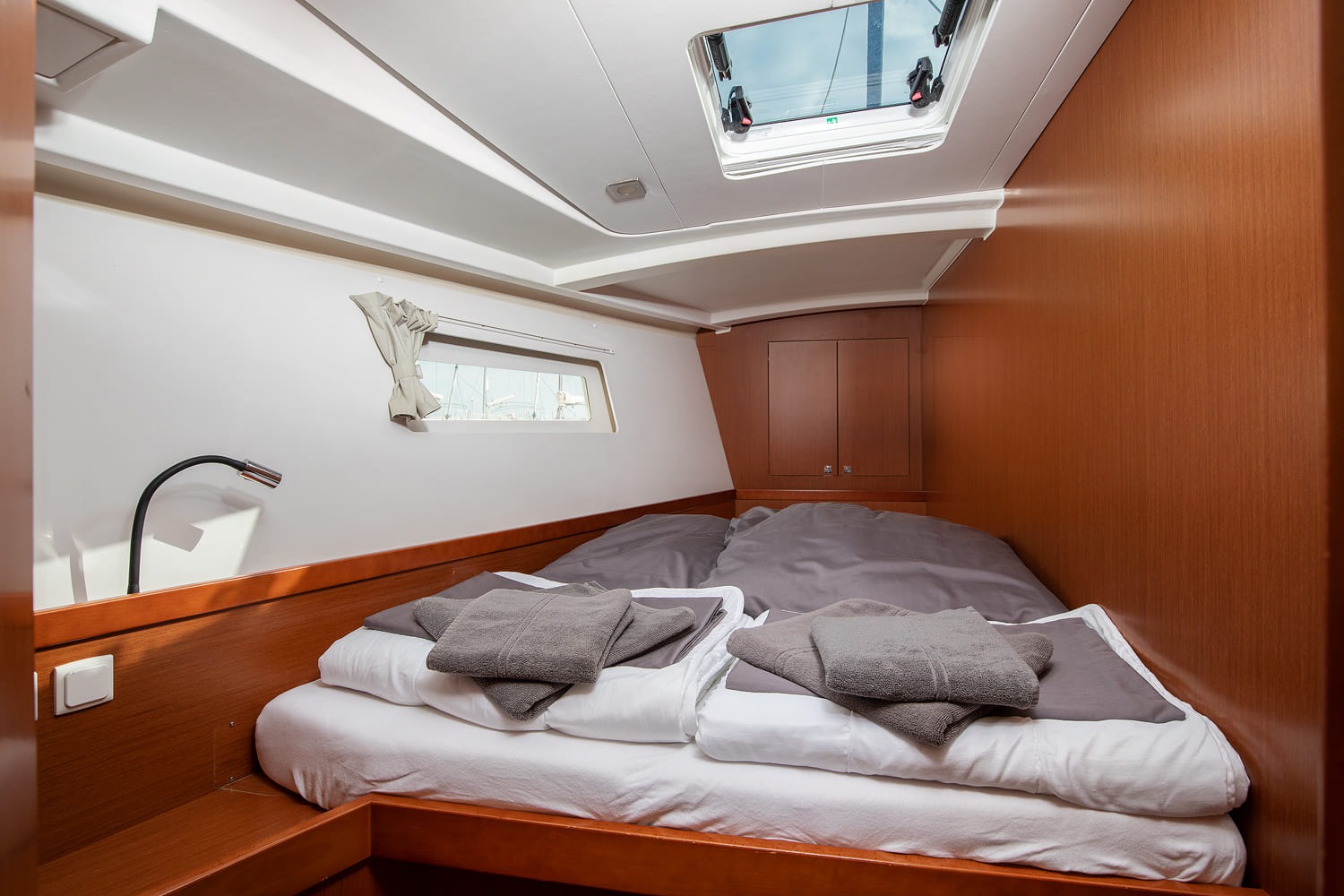 Double cabin aboard the Oceanis 45, with island berth, opening hatch, hanging locker and folded towels