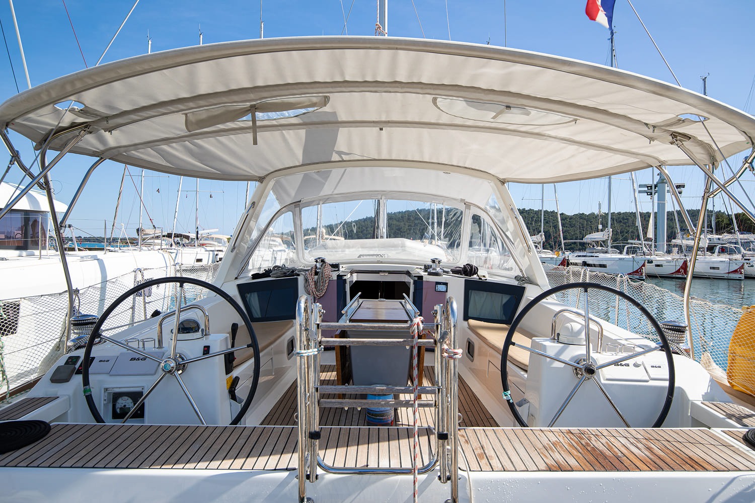 Cockpit of Mare Aeolos under the bimini, with twin B&G helms, folding table and companionway steps
