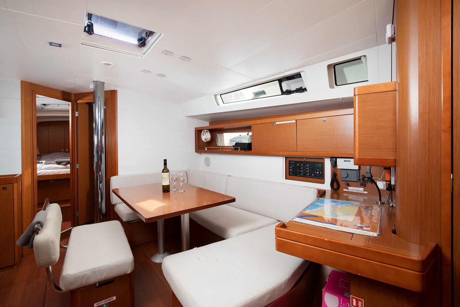 Saloon dining table and L-shaped settee of Mare Aeolos, with chart table and B&G instrument panel to starboard